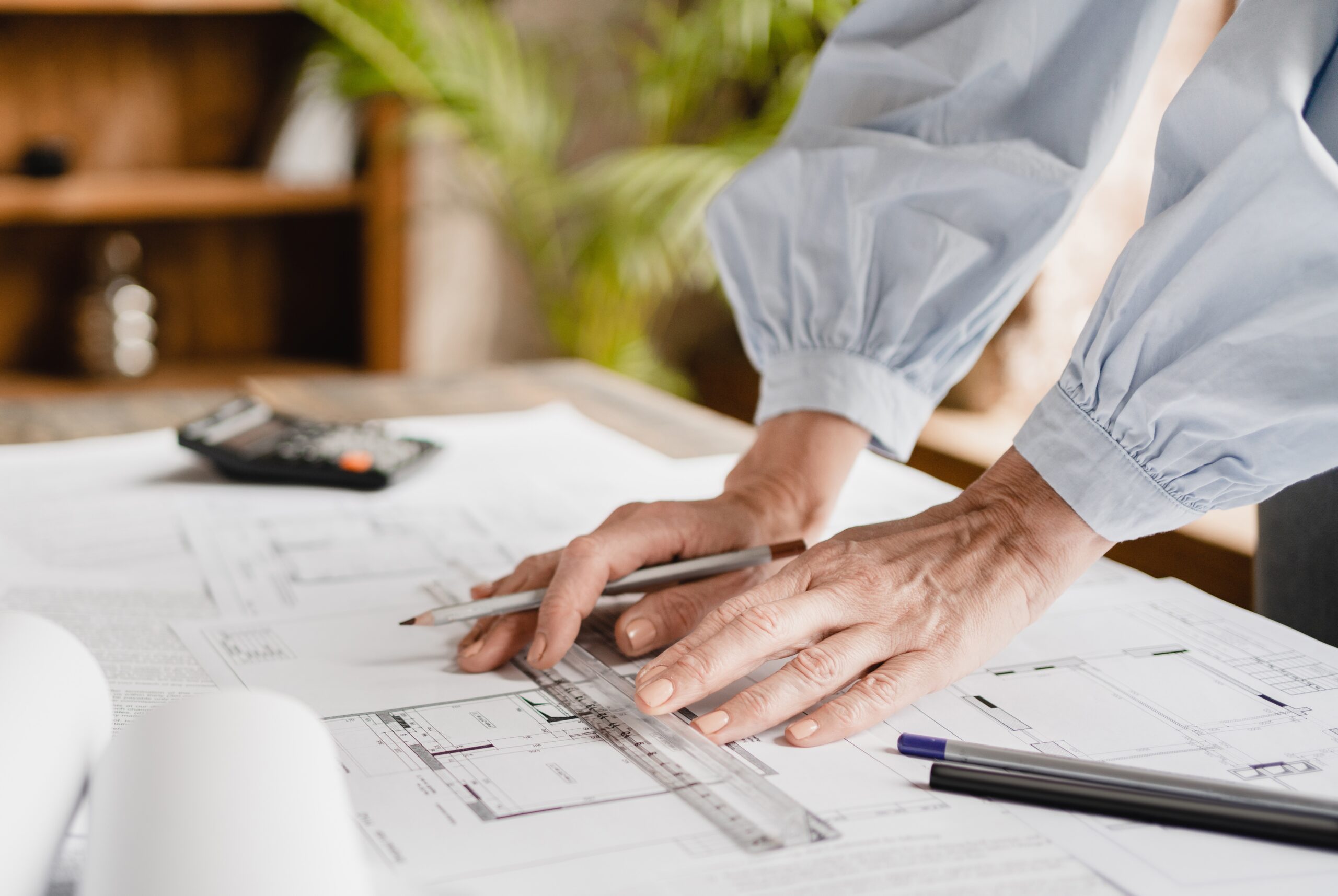 Architecte d'intérieur traçant sur des plans, règle et crayon en main